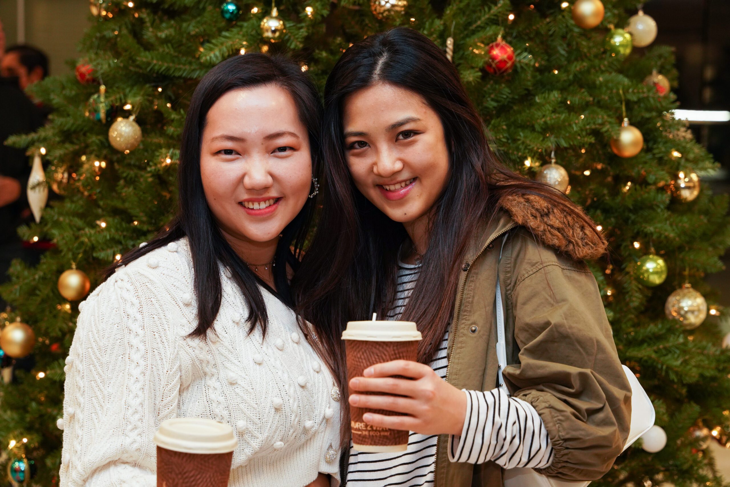 picture of two women smiling, their background is a christmas tree